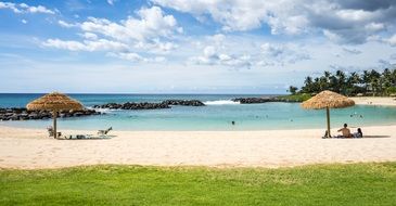 Beautiful sandy beach with people near the grass of Ko Olina Resort in Hawaii