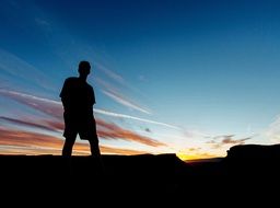 photo of silhouette of a man on a mountain during sunset