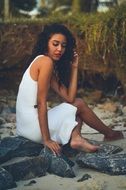 girl in a white dress sitting on a stone