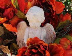 white Angel sculpture and red flower in a garden