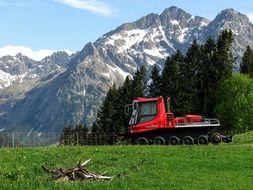 snowmobile on a green meadow at the foot of the mountains