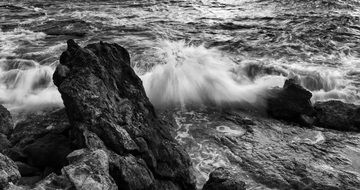 black and white photo waves beat against the rocks