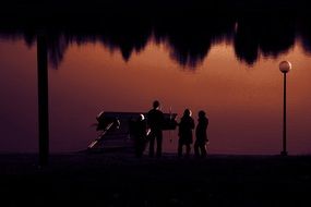 silhouettes of people near the lake in colorful twilight