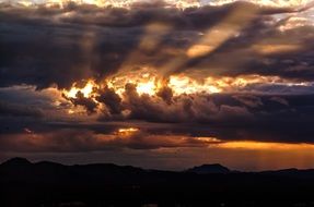 bright rays of the sun through dark clouds over a plain