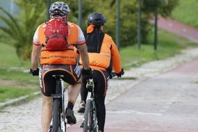 cyclists in orange vests ride in the park