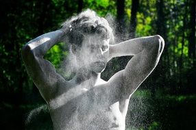 young man shakes off dust from himself in nature