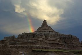a rainbow in the sky behind a rocky mountain
