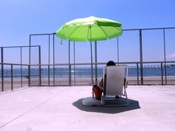 person sits in armchair under parasol in front of sea, brasil, Rio De Janeiro, Baia De Guanabara