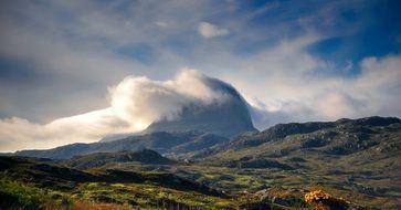 distant view of a bright mountain of suilven in white clouds