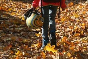 man walking through the woods with a helmet in his hands