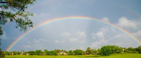 Beautiful and colorful rainbow above the houses among the colorful plants