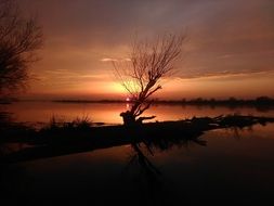 Beautiful, orange sunset over the beautiful river with silhouettes