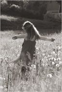 black and white photo of a girl among meadow flowers