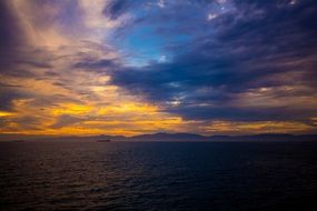 Beautiful ocean waterscape with the boat under colorful sunset in the clouds