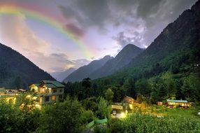rainbow in the cloudy sky above the high hills
