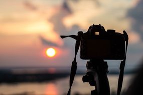 camera on a tripod on the background of the sunrise