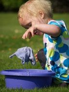 child with a purple basin and washcloth on the lawn