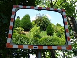 road mirror in a white-red frame in the forest