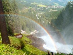 Beautiful and colorful rainbow on Krimml waterfall with green trees in Salzburg, Austria