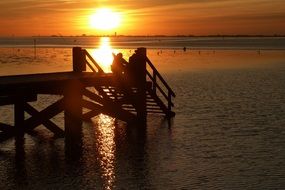 wooden pier in the rays of a sunset on the north sea