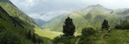rainbow over green alpine hills