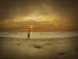 Man Walking on the sandy beach at beautiful and colorful sunrise