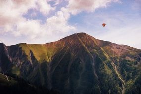 hot air balloon over mountains on a sunny day