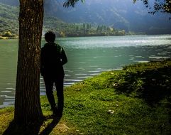 Thoughtful person near the lake on the landscape