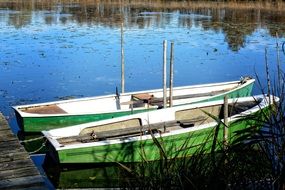two wooden green boats near the pier on the lake