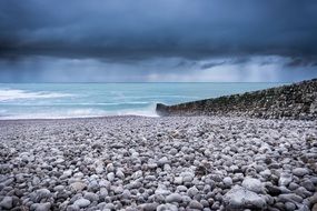 landscape of pebbles beach under a cloudy sky in normandy