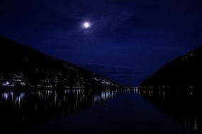 white moon in the night sky over the port city