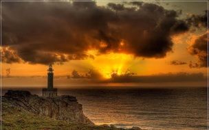 lighthouse on the seashore against the backdrop of a fiery sunset