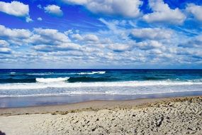 Beautiful sandy beach under blue sky with white clouds on Earth Day