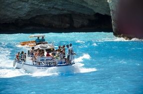 pleasure boat with tourists on turquoise water off the coast of Greece