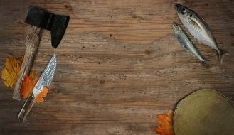 raw fish, axe and knife on wooden table