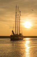 sailing ship on glossy sea at sunset