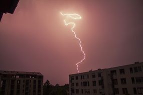 lightning in pink night sky over buildings