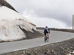 man cycling by curved mountain road, france, Col De La Bonette