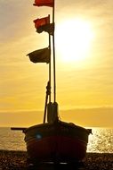 standing boat with flags at sunset