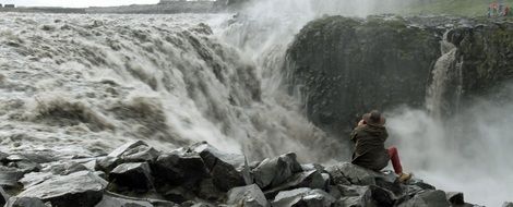 man on stones near waterfall