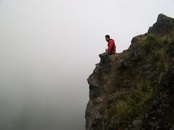 man sitting on the cliff edge