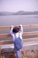 Korean boy in denim overalls climbs the fence