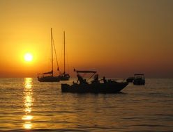 boats on the ocean against the backdrop of the bright setting sun