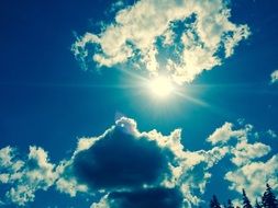 Sun shines among clouds in blue Sky