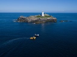 Lighthouse on island and Fishing Boats at deep blue sea, uk, england, cornwall