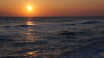 Reflection of the orange and yellow light of the Sun on the beautiful surface of a calm sea