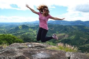 photo of a jumping girl on top of a mountain