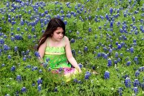 girl sits among flowers in a clearing