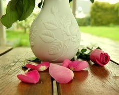 pink petals of roses near a vase of flowers