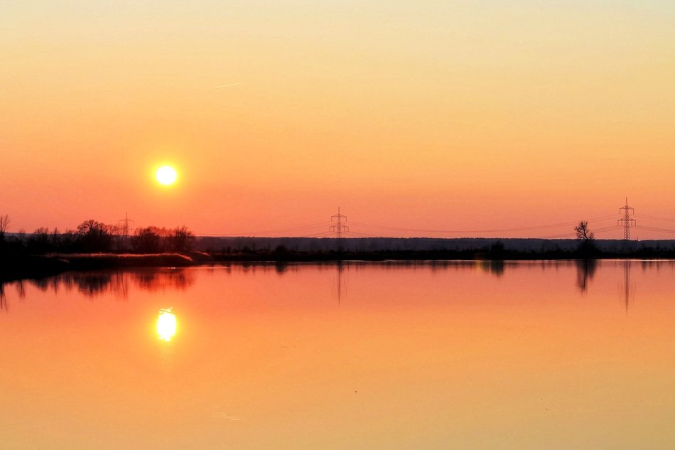 orange sunset is mirrored in the lake